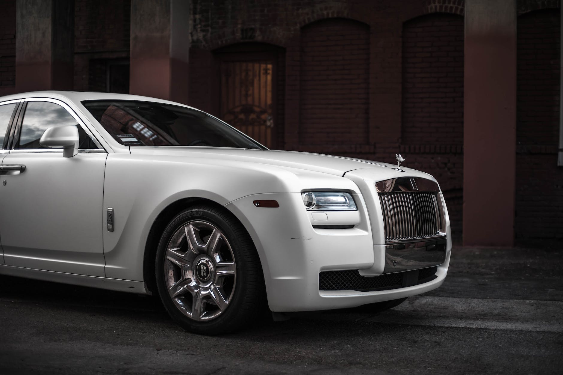 photo of white rolls royce ghost parked near brown building